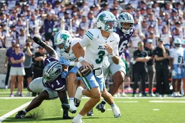 Football player in white jersey #3 runs past a diving defender on a green field during a game
