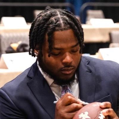 A man in a suit and tie is signing a football