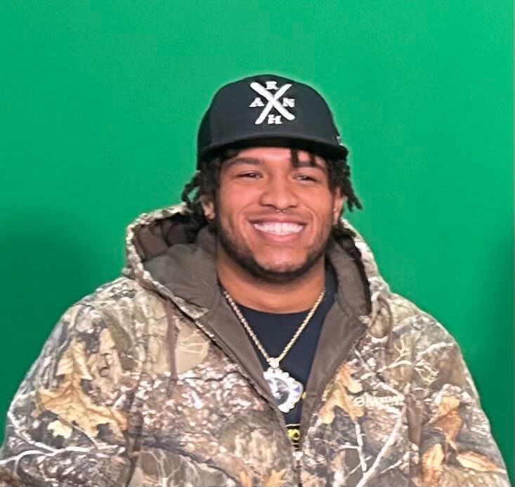 A man wearing a hat with the letter x on it