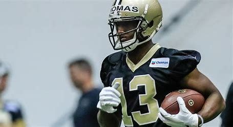 A football player wearing a helmet and number 13 jersey is running with a football.