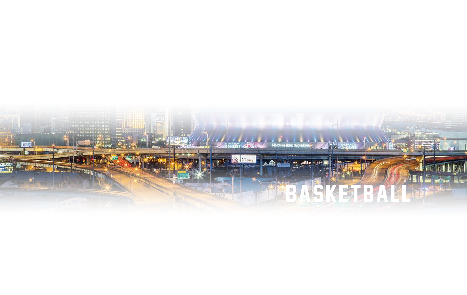 A basketball stadium in the middle of a city at night.