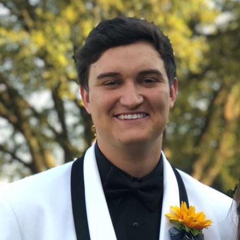 A man in a tuxedo and bow tie is smiling for the camera.