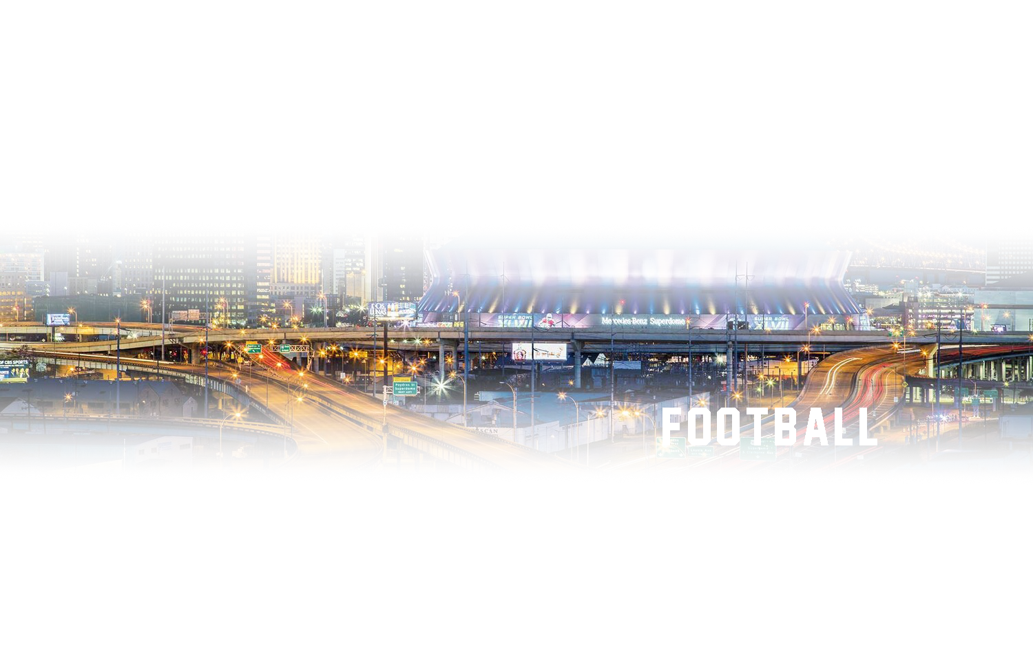 A football stadium in the middle of a city at night.