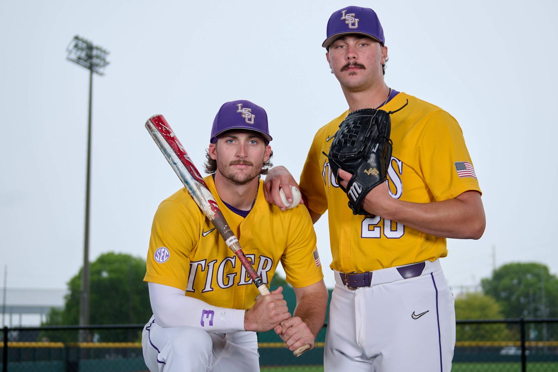 Two baseball players are posing for a picture on a field.