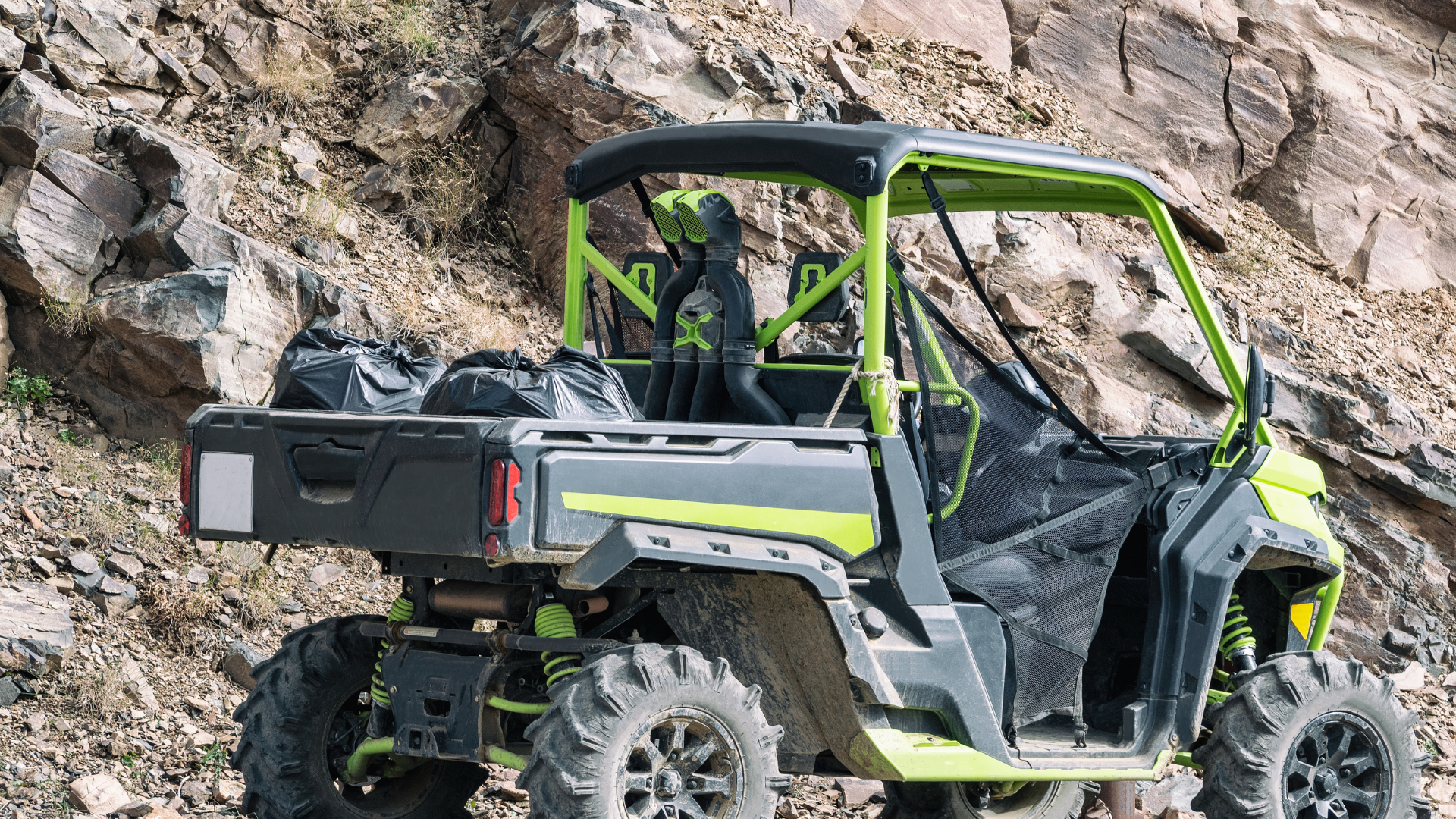 The inside of a utility vehicle with a steering wheel and a propane tank in the background.