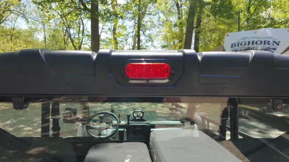 The rear view mirror of a utv with a red light on it.