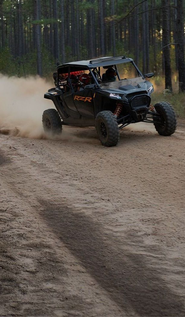 A man is driving a polaris rzr with a gps on the dashboard.