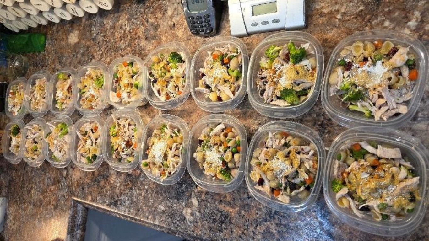 Rows of clear meal prep bowls with rice, chicken, and vegetables on a countertop
