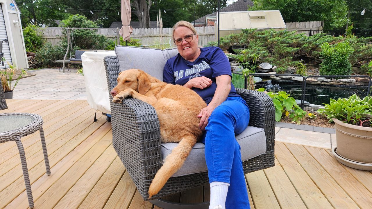 A woman is sitting in a chair with a dog on her lap.