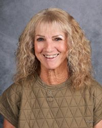 A woman with blonde hair and a green shirt is smiling for the camera.