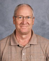 A man wearing glasses and a polo shirt is smiling for the camera.