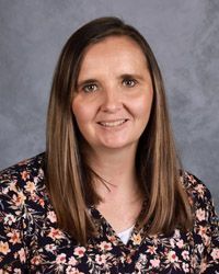 A woman in a floral shirt is smiling for a picture.