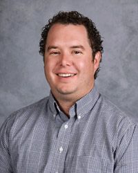 A man in a plaid shirt is smiling for the camera.