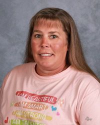 A woman in a pink t-shirt is smiling for the camera.