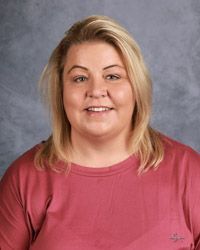 A woman in a red shirt is smiling for the camera.