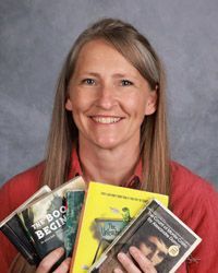 A woman is holding a bunch of books in her hands.
