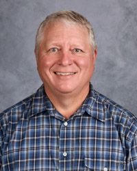 A man in a blue plaid shirt is smiling for the camera.