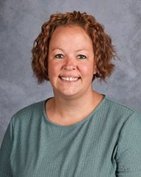 A woman in a green shirt is smiling for a picture.