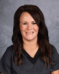 A woman in a black scrub top is smiling for a picture.