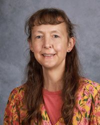 A woman in a floral shirt is smiling for a picture.