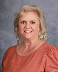 A woman in a red shirt is smiling for a picture.
