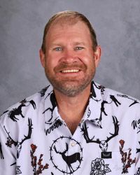 A man with a beard is wearing a white button up shirt with deer print