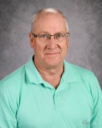 Head-and-shoulders portrait of a man in a mint green polo shirt against a gray studio backdrop