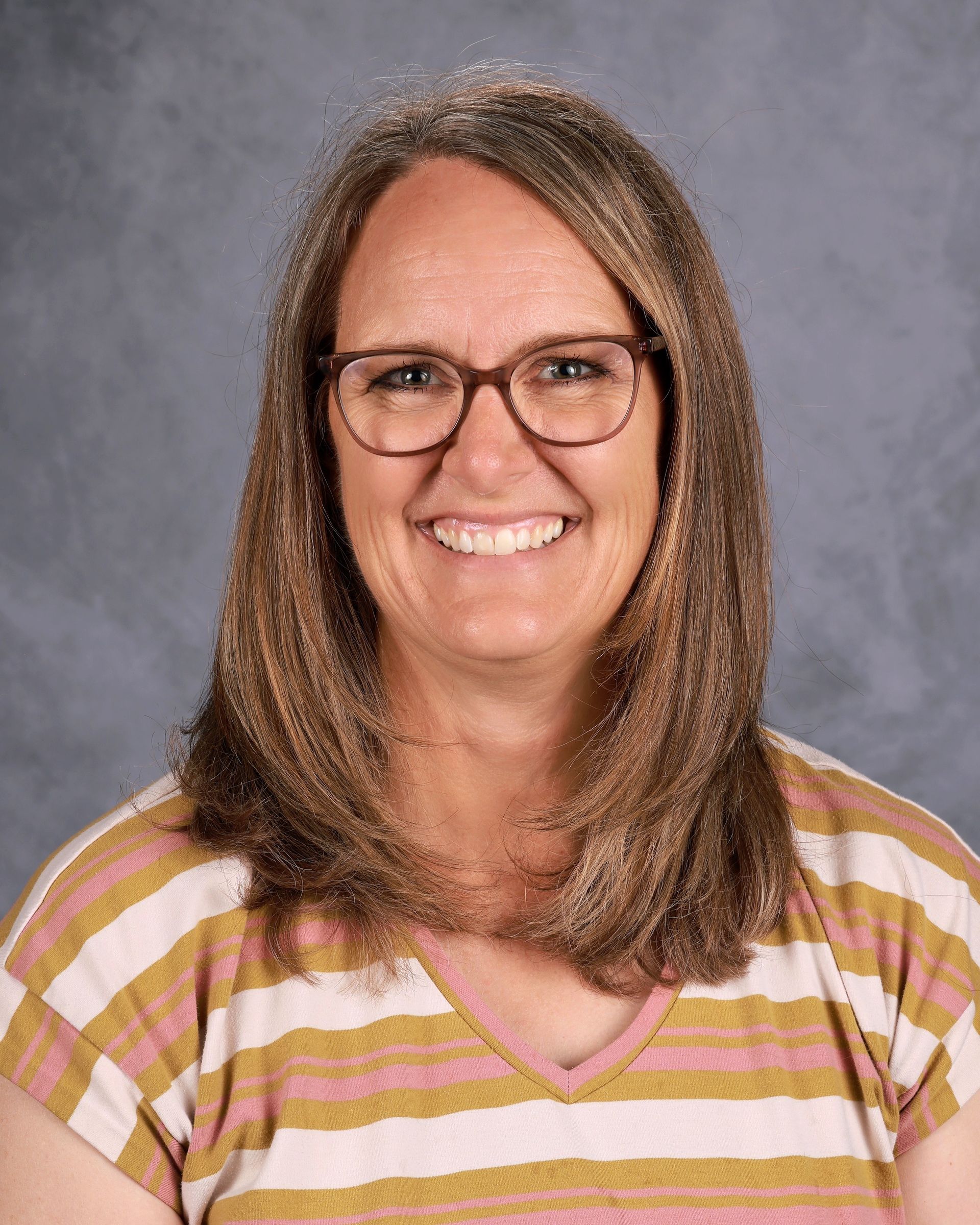 A lady in a tan and cream stripe shirt smiling for the camera.