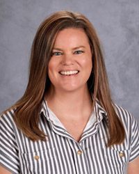 A woman gray and white striped shirt is smiling for the camera.
