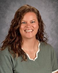 Smiling woman in a green top against a gray studio backdrop