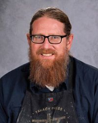 A man with a beard and glasses is wearing a black shirt.