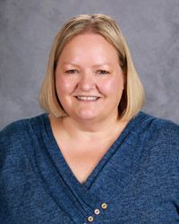 A woman in a blue shirt is smiling for a picture.