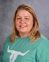 A woman in a green shirt is smiling for the camera.