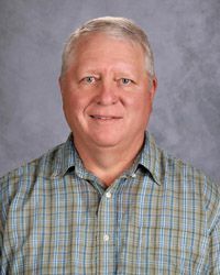 A man in a green plaid shirt is smiling for the camera.