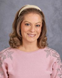 A woman in a pink shirt is smiling for the camera.
