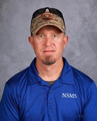 A man wearing a hat and sunglasses, blue polo shirt is posing for a picture.