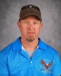 Portrait of a man in a blue polo shirt and cap against a gray backdrop