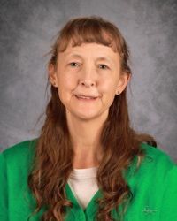 Portrait of a woman in a green top against a gray studio backdrop