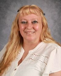Smiling woman in a white blouse against a gray studio backdrop