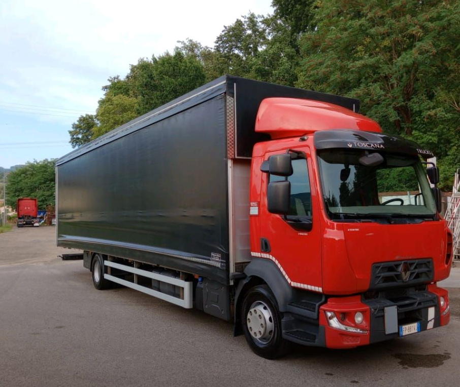 Un camioncino Renault rosso e nero su una strada asfaltata, parcheggiato davanti agli alberi.