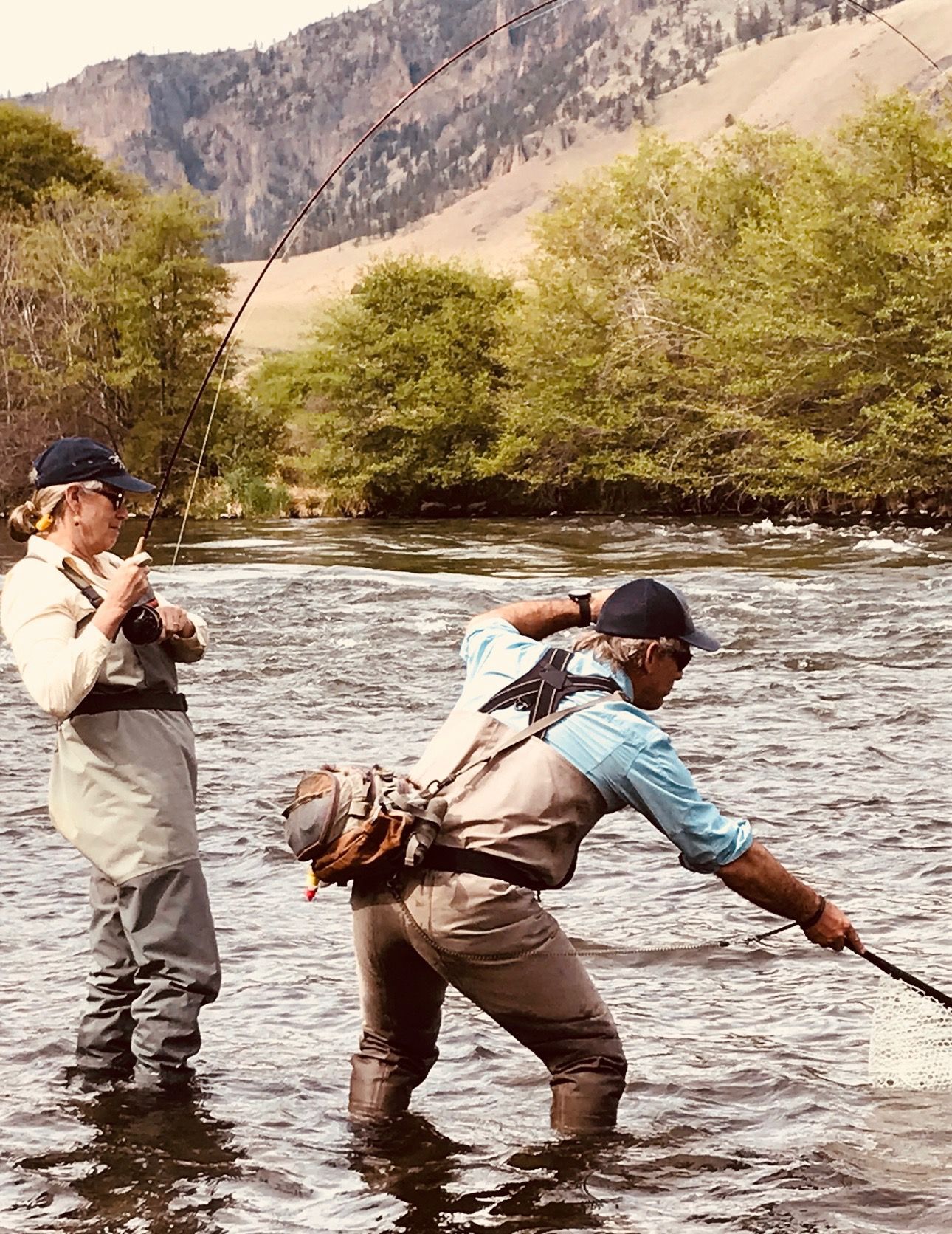A man and a woman are fishing in a river.