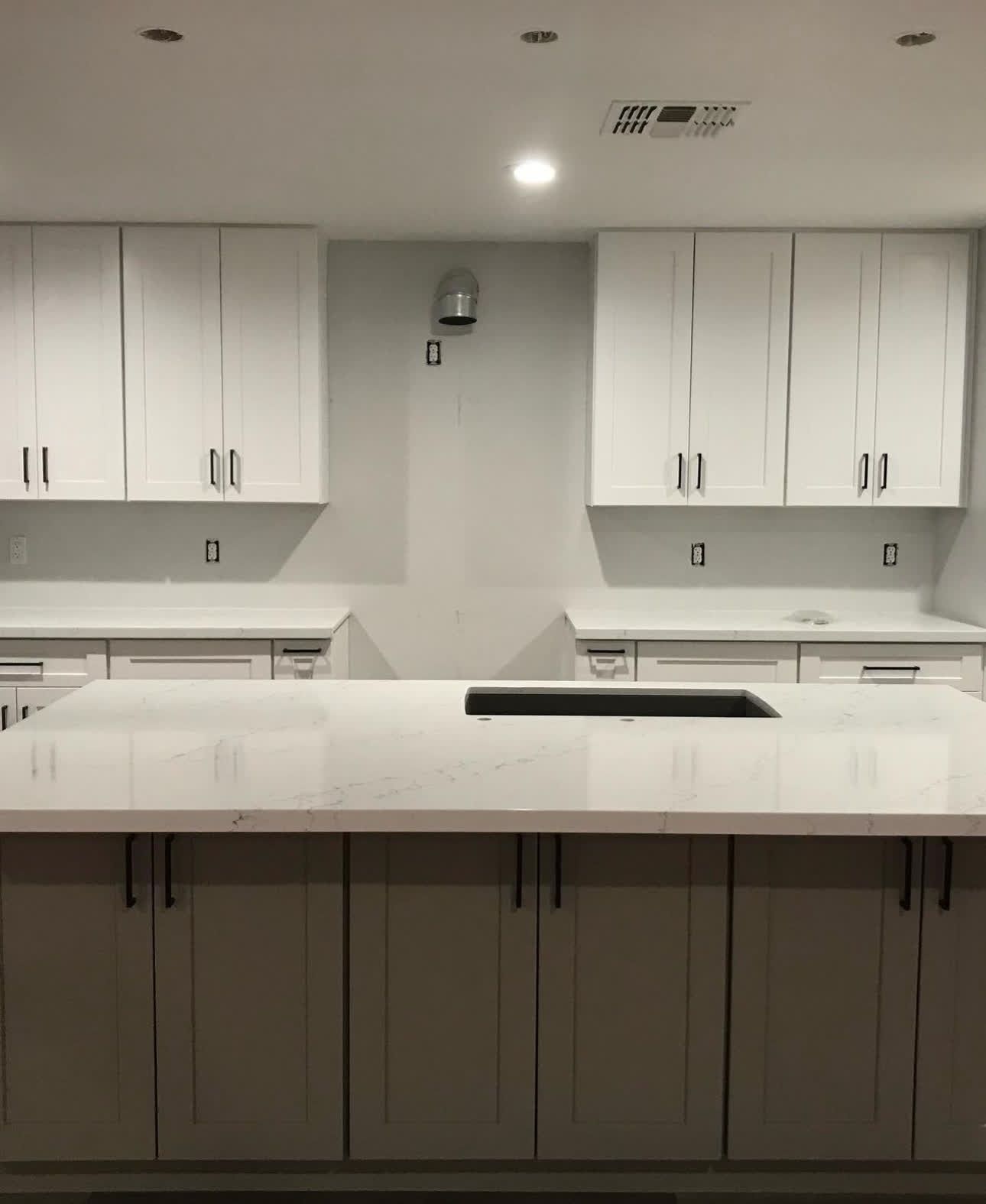 A kitchen with white cabinets and a white counter top