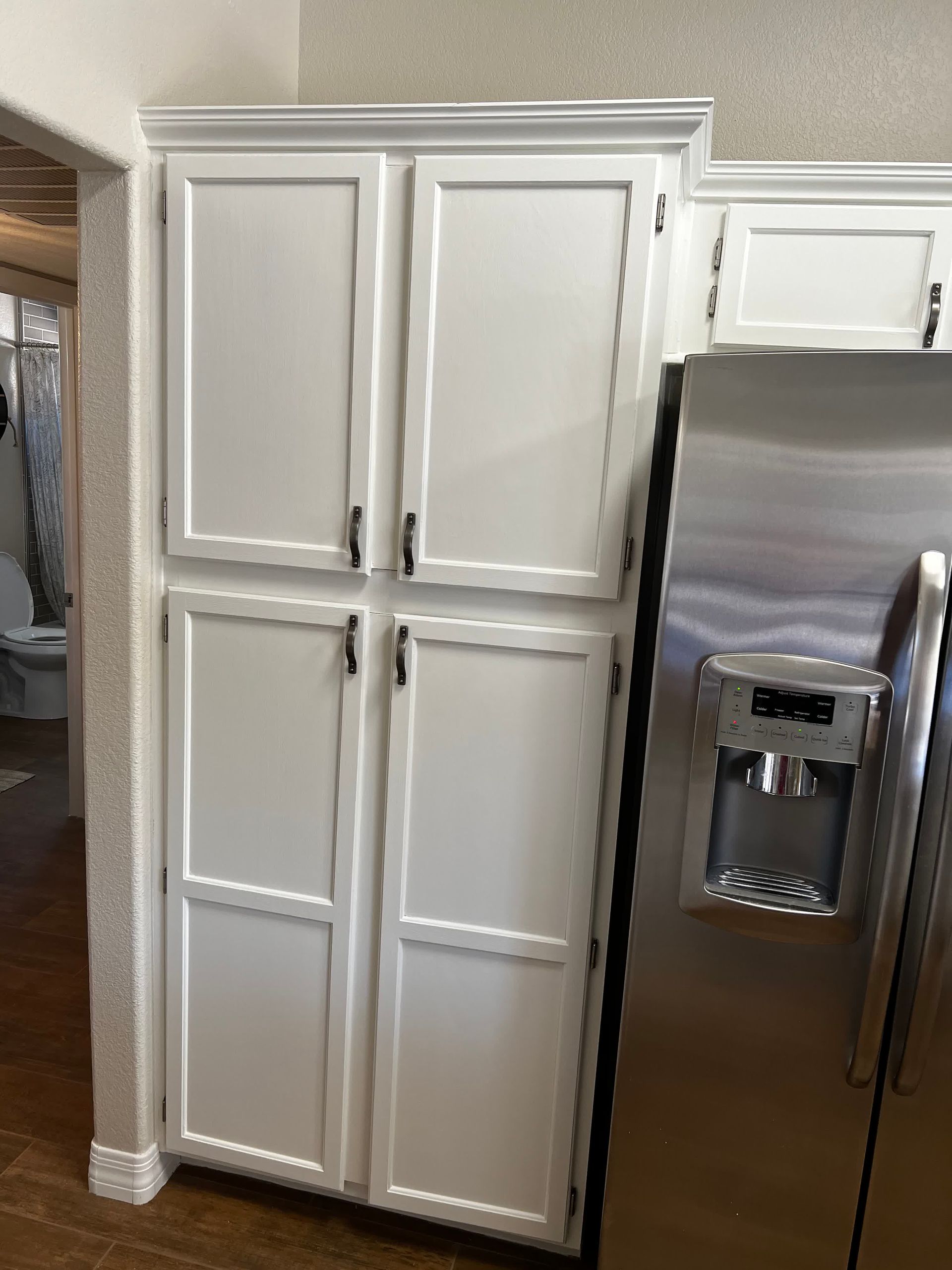 A kitchen with white cabinets and a stainless steel refrigerator.