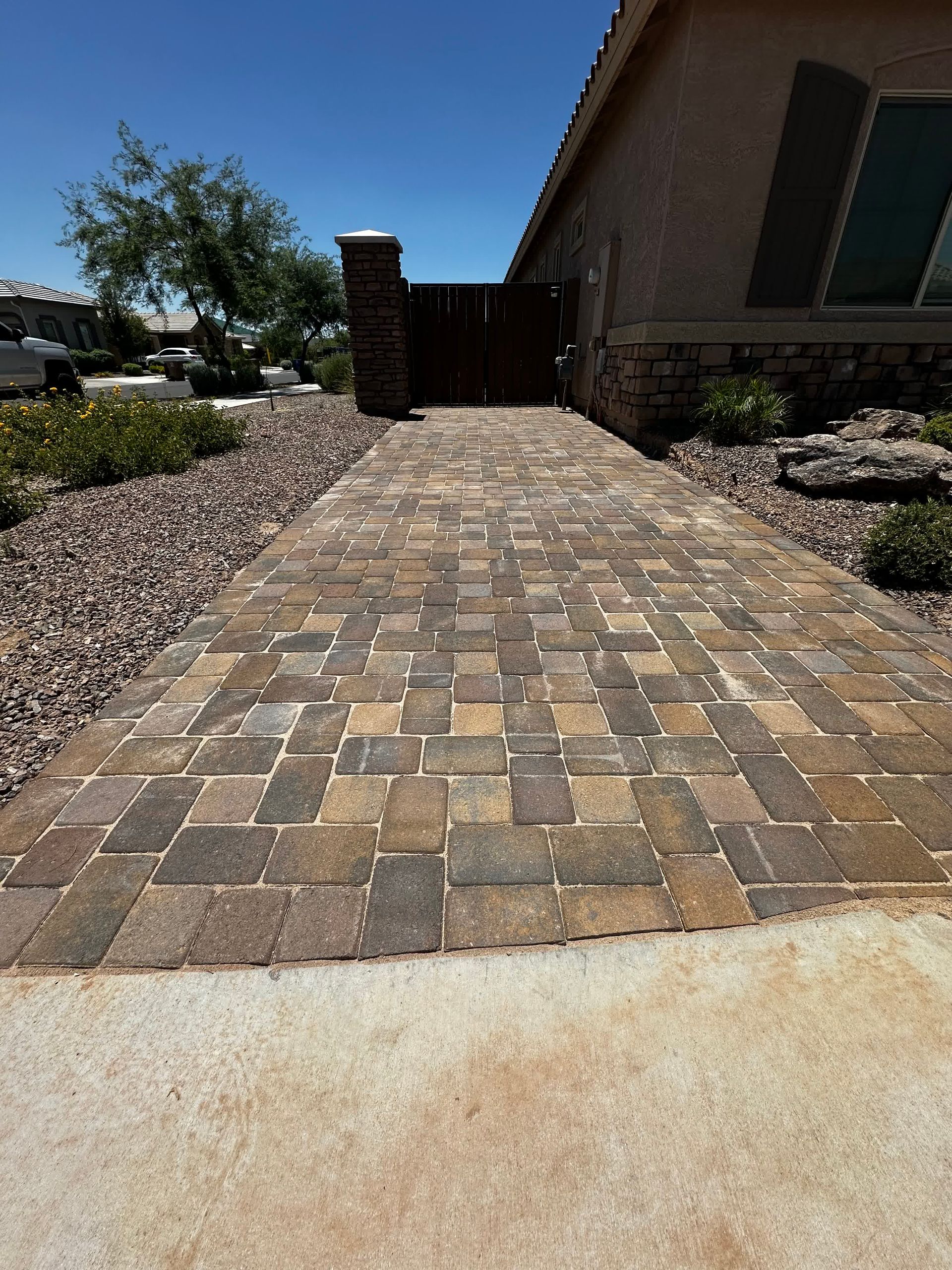A brick walkway leading to a house on a sunny day