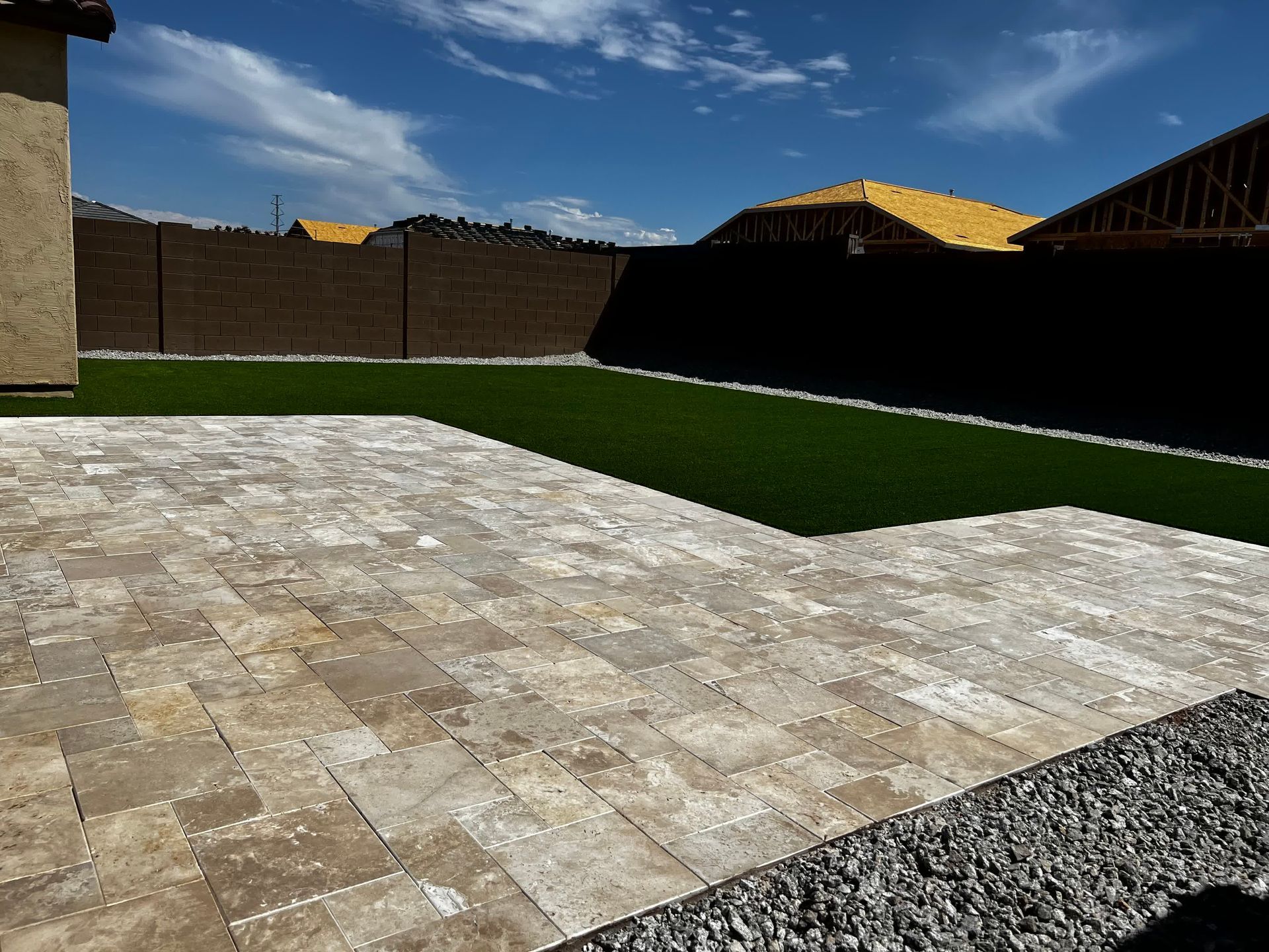A patio with a lawn in the background and a house in the background.