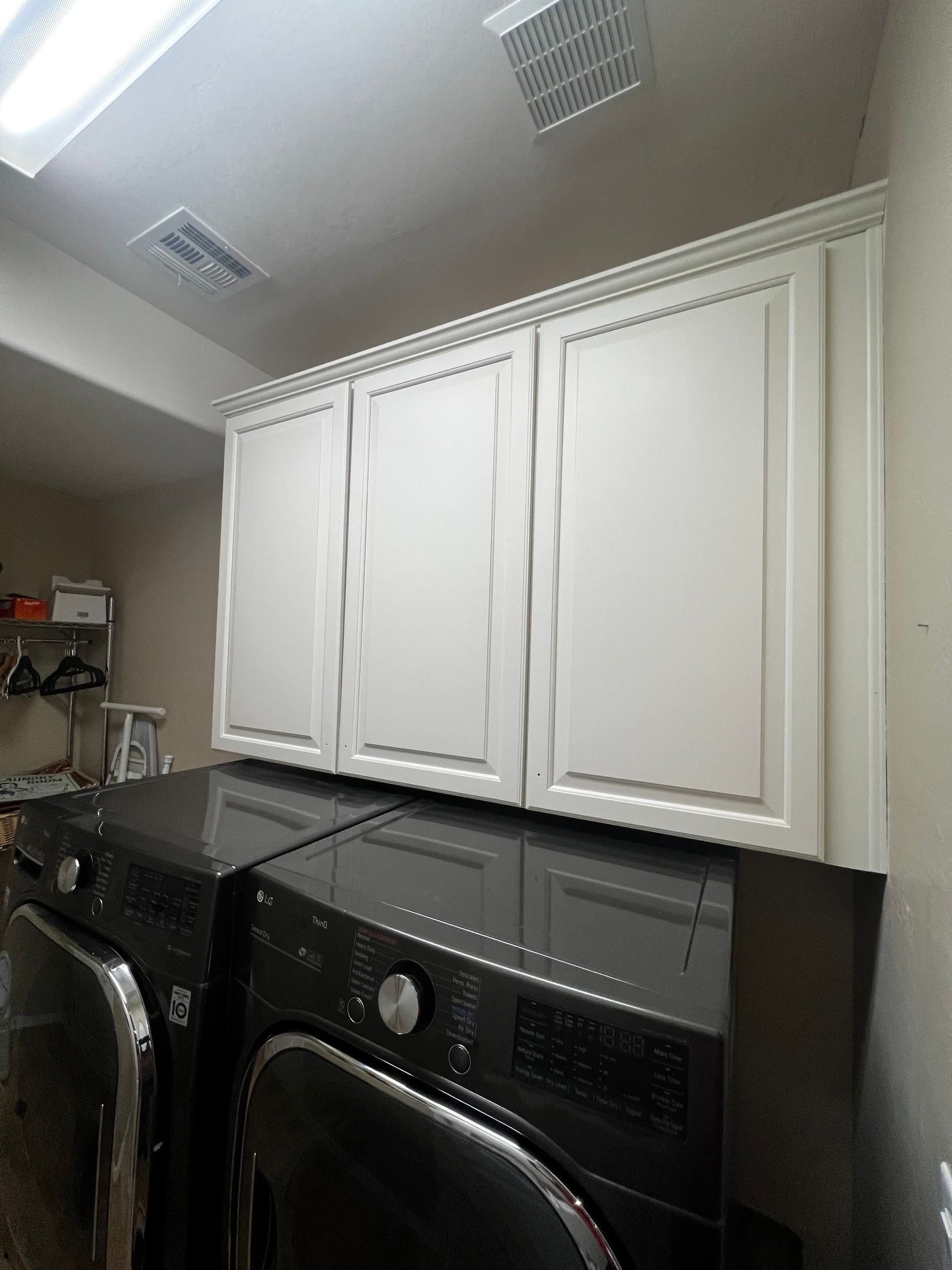 A laundry room with a washer and dryer and white cabinets.