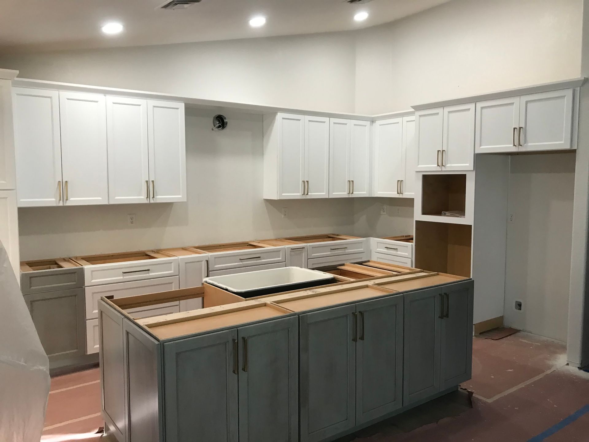 A kitchen under construction with white cabinets and a large island.