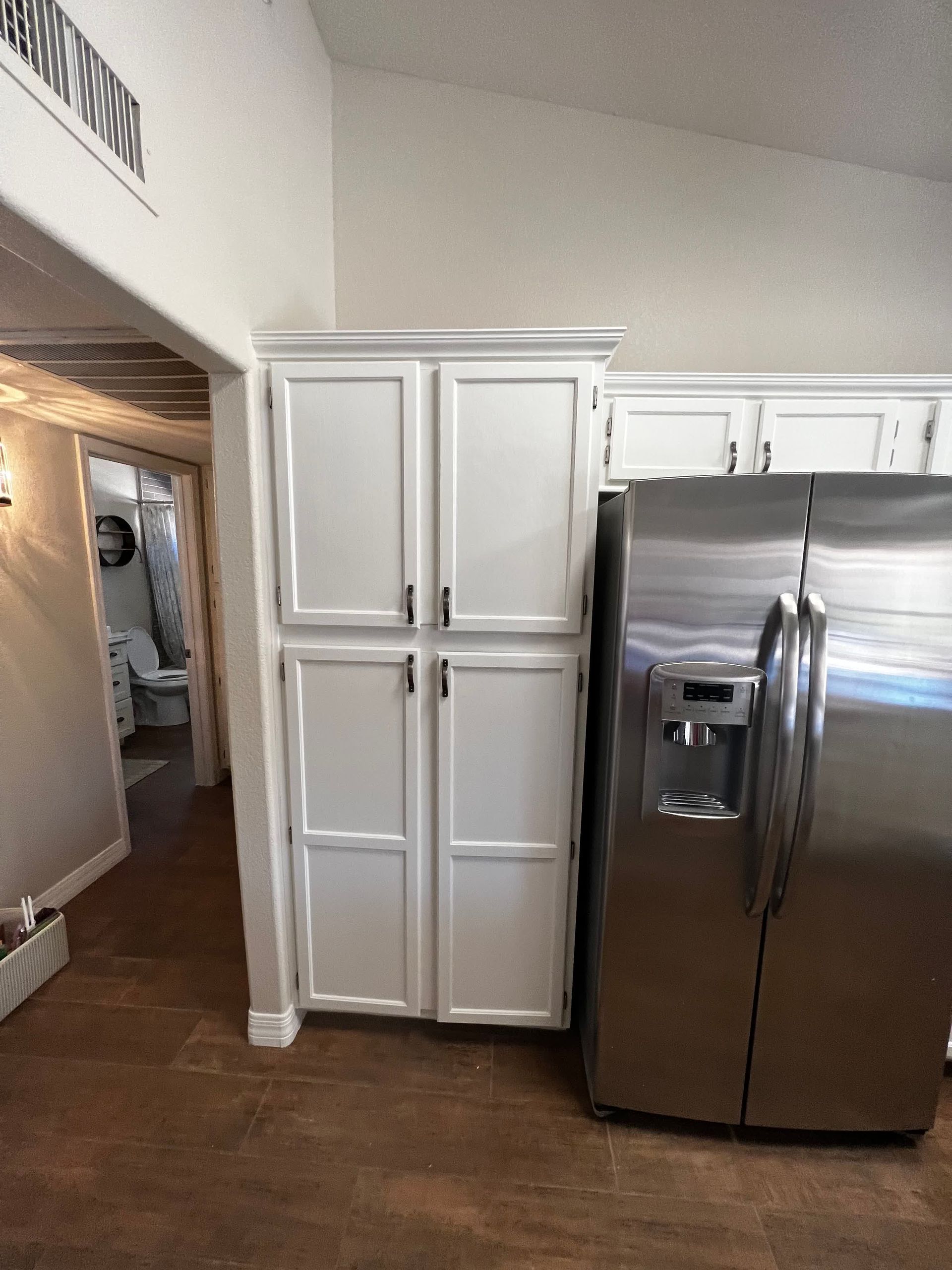 A kitchen with white cabinets and a stainless steel refrigerator