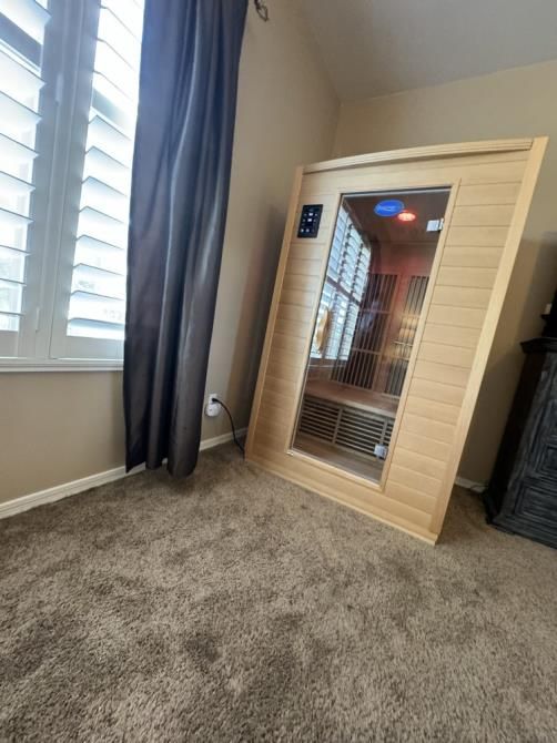 An infrared sauna is sitting in a bedroom next to a window.