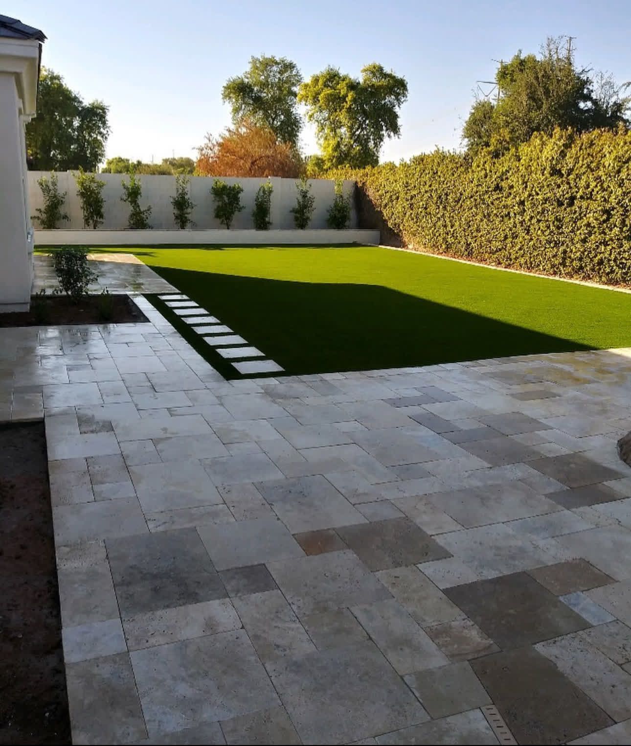 A tiled patio with a lush green lawn in the background